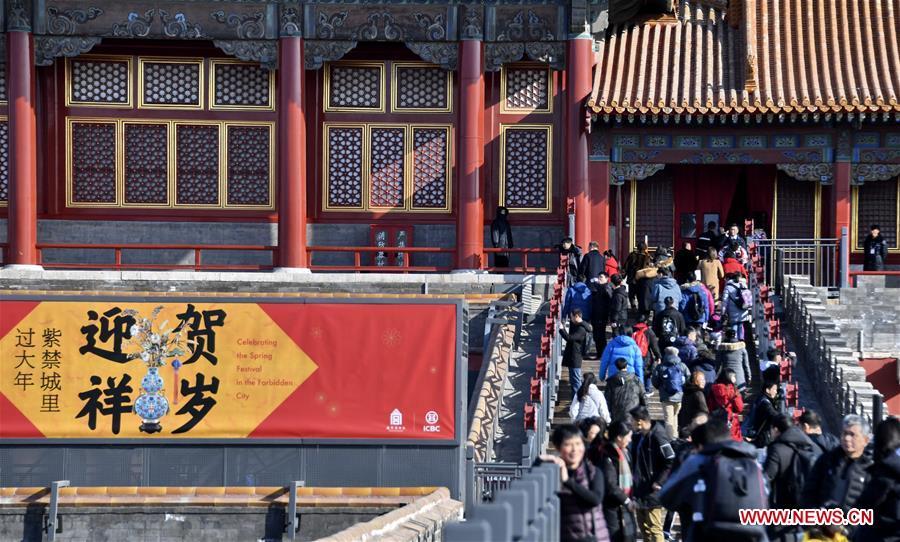 Tourists walk past a poster celebrating the Spring Festival in the Palace Museum, also known as the Forbidden City, in Beijing, capital of China, Jan. 25, 2019. The Palace Museum is decorated to celebrate the upcoming Spring Festival, or the Chinese Lunar New Year, which falls on Feb. 5 this year. (Xinhua/Li Xin)