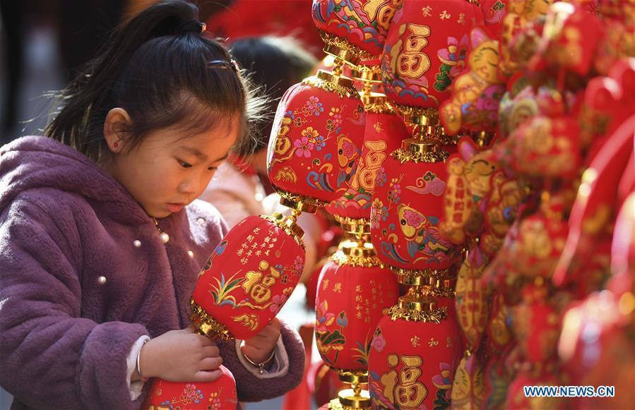A child looks at Spring Festival decoration at a market in Hefei, capital of east China\'s Anhui Province, Jan. 26, 2019. Red decorations are arranged across China to greet the upcoming lunar New Year which will fall on Feb. 5 this year. (Xinhua/Liu Qinli)