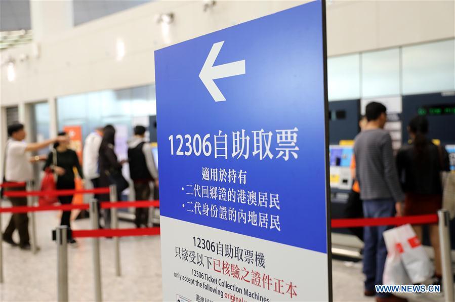 Passengers take their tickets from automotive ticket machines at the West Kowloon railway station in Hong Kong, south China, Jan. 25, 2019. To better serve the passengers using the automotive ticket machines, blue signs are installed and staff members in orange are dispatched to offer help at the West Kowloon railway station in Hong Kong. (Xinhua/Wu Xiaochu)