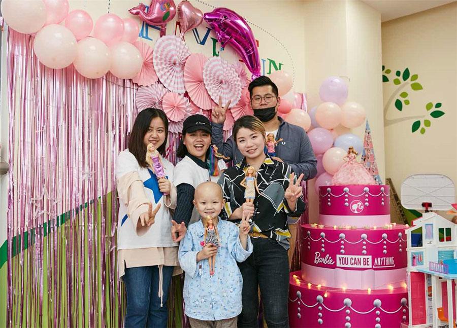 Volunteers and Xinyi take a group picture in the ward decorated to a Barbie theme at Shanghai Xinhua Hospital. (Photo provided to chinadaily.com.cn)