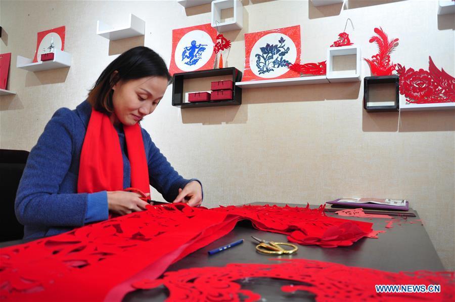 Craftswoman Liang Ying creates papercutting works of cheongsam at her studio in Liaocheng, east China\'s Shandong Province, Jan. 30, 2019. Liang Ying made 18 papercutting works of cheongsam to greet the upcoming Spring Festival, which falls on Feb. 5 this year. (Xinhua/Xu Wenhao)