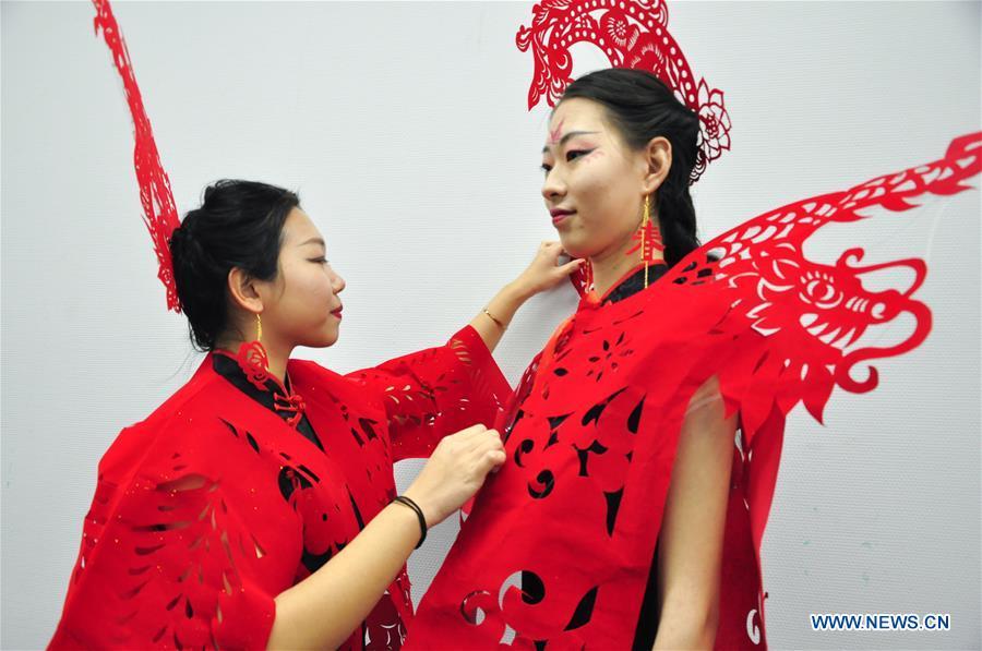 Cheongsam enthusiasts arrange papercutting works of cheongsam made by craftswoman Liang Ying at her studio in Liaocheng, east China\'s Shandong Province, Jan. 30, 2019. Liang Ying made 18 papercutting works of cheongsam to greet the upcoming Spring Festival, which falls on Feb. 5 this year. (Xinhua/Xu Wenhao)
