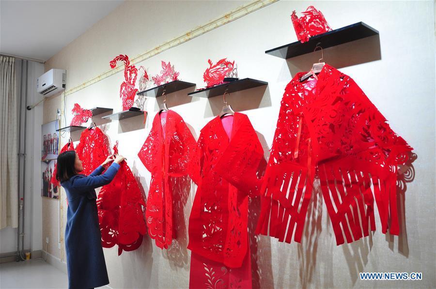 Craftswoman Liang Ying arranges her papercutting works of cheongsam at her studio in Liaocheng, east China\'s Shandong Province, Jan. 30, 2019. Liang Ying made 18 papercutting works of cheongsam to greet the upcoming Spring Festival, which falls on Feb. 5 this year. (Xinhua/Xu Wenhao)