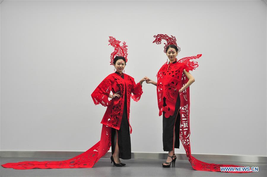 Cheongsam enthusiasts display papercutting works of cheongsam made by craftswoman Liang Ying at her studio in Liaocheng, east China\'s Shandong Province, Jan. 30, 2019. Liang Ying made 18 papercutting works of cheongsam to greet the upcoming Spring Festival, which falls on Feb. 5 this year. (Xinhua/Xu Wenhao)