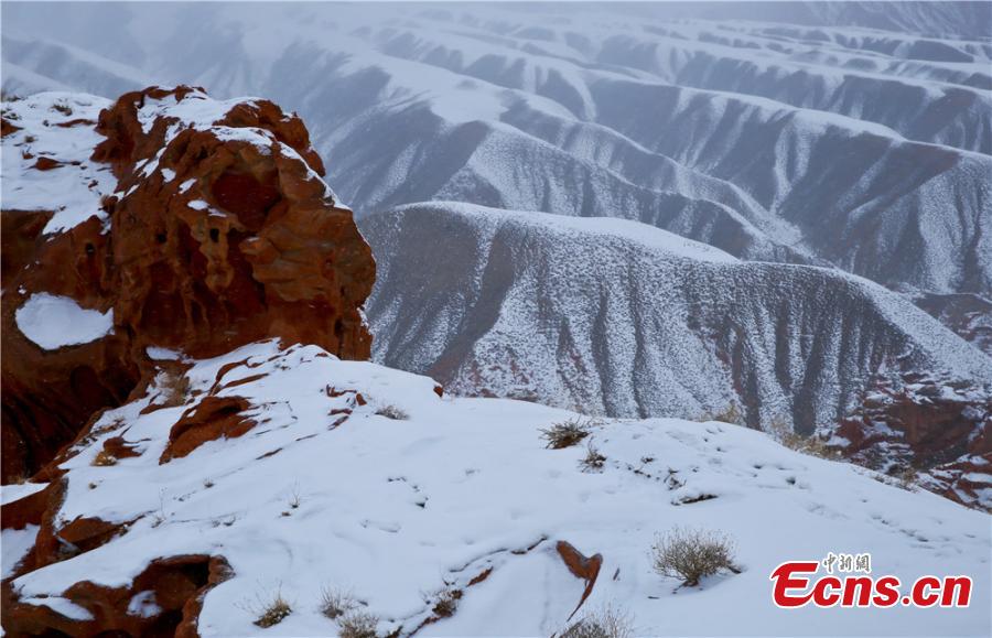 Tourists visit the snow-covered Danxia landform in Sunan Yugur Autonomous County, Northwest China\'s Gansu Province during the Spring Festival holiday. The Danxia landform is a unique type of geomorphology formed from red-colored sandstone and characterized by steep cliffs. (Photo: China News Service/Wang Jiang)