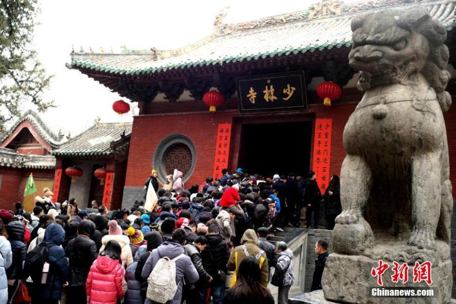 Students of kung fu at Shaolin Temple pose with Transformer-like statues in Dengfeng City, Central China\'s Henan Province, Feb. 7, 2019, as many tourists visit the famed Buddhist temple during the Lunar New Year holiday. (Photo: China News Service/Wang Zhongju)