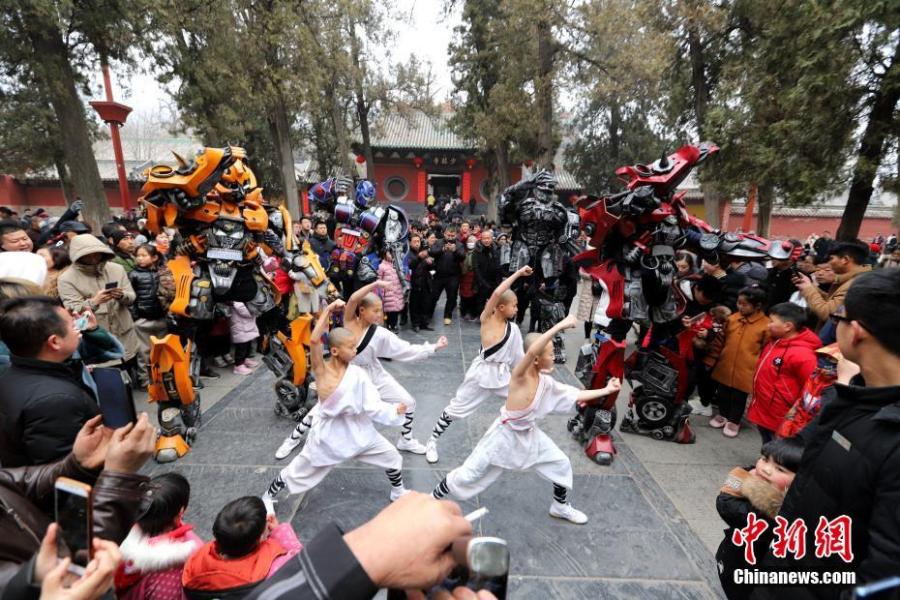 Students of kung fu at Shaolin Temple pose with Transformer-like statues in Dengfeng City, Central China\'s Henan Province, Feb. 7, 2019, as many tourists visit the famed Buddhist temple during the Lunar New Year holiday. (Photo: China News Service/Wang Zhongju)