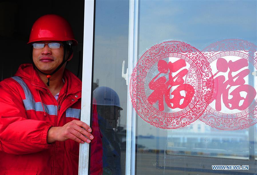 Gong Fuqiang, a crane driver, looks out of the door of a rest room at Zhenghe Xinggang Terminals of Taicang Port in Suzhou, east China\'s Jiangsu Province, Feb. 11, 2019, the first workday after Spring Festival holiday. (Xinhua/Ji Haixin)