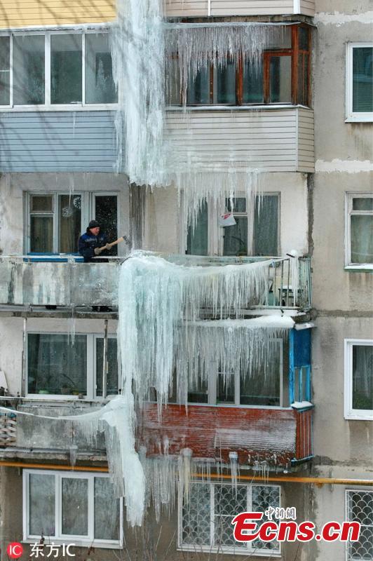 A man moves ice on a residential building in Ivanovo, Russia, Feb. 11, 2019. (Photo/IC)