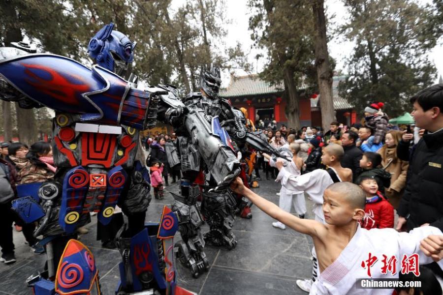 Students of kung fu at Shaolin Temple pose with Transformer-like statues in Dengfeng City, Central China\'s Henan Province, Feb. 7, 2019, as many tourists visit the famed Buddhist temple during the Lunar New Year holiday. (Photo: China News Service/Wang Zhongju)