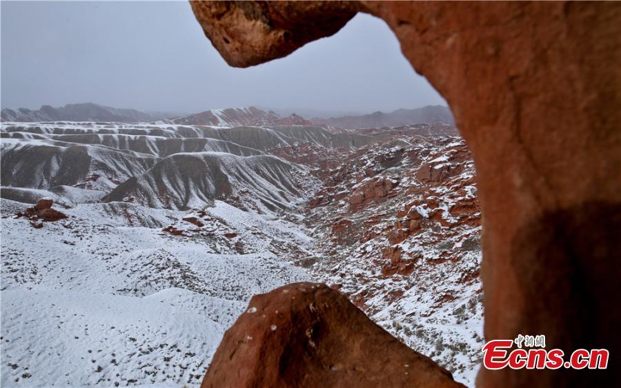 Tourists visit the snow-covered Danxia landform in Sunan Yugur Autonomous County, Northwest China\'s Gansu Province during the Spring Festival holiday. The Danxia landform is a unique type of geomorphology formed from red-colored sandstone and characterized by steep cliffs. (Photo: China News Service/Wang Jiang)
