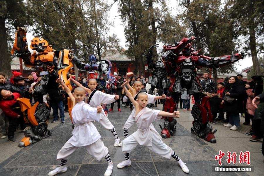 Students of kung fu at Shaolin Temple pose with Transformer-like statues in Dengfeng City, Central China\'s Henan Province, Feb. 7, 2019, as many tourists visit the famed Buddhist temple during the Lunar New Year holiday. (Photo: China News Service/Wang Zhongju)