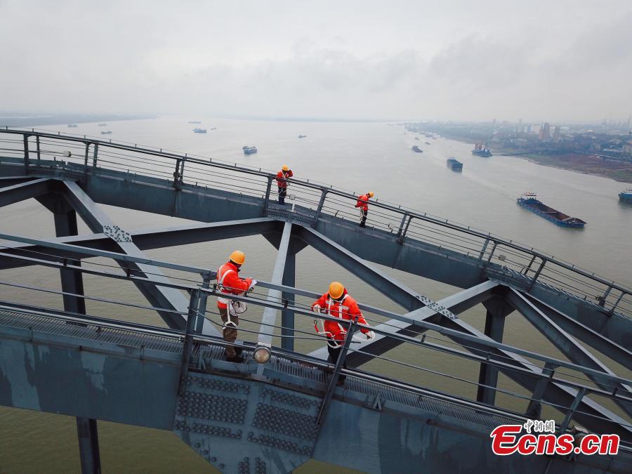 Technicians conduct a routine safety check on the Jiujiang Yangtze River Bridge, a major connection of the Beijing-Kowloon Railway in Jiujiang City, East China\'s Jiangxi Province during the travel peak of the Spring Festival. Despite the wind and vibration caused by the passing trains, they continued working in baskets hung under the bridge\'s girder, about 20 meters above the rolling Yangtze River. (Photo: China News Service/Ding Bo)