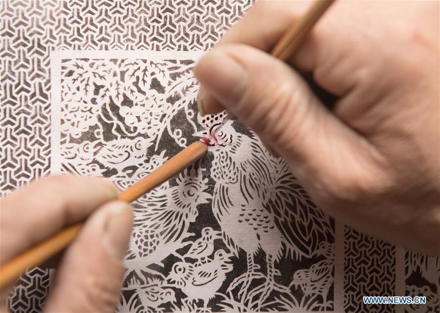 Lin Shunkui shows paper-cutting skills at home in Beibaixiang Town of Yueqing, east China\'s Zhejiang Province, Feb. 12, 2019. Having a history of more than 400 years, the ornamental dragon, a sacrifice to pray for good fortune during the period of Lantern Festival, is popular in villages of Yueqing City in Zhejiang Province. Lin Shunkui, an inheritor of the handicraft of ornamental dragon, is born in 1956 in Dongchan Village of Beibaixiang Town. Learning the art since he was young from his father, who is a master of fine paper-cutting, Lin has been in the walk for more than 40 years and has been famous for his exquisite handicraft. The making procedures of the ornamental dragon require high standards and needs preparation of more than half a year. The craftsman must be proficient in various vocations such as paper-cutting, carpentry, painting and machinery. Usually having a height of four meters, a length of three meters and a width of two meters, the ornamental dragon displays about 300 figures in more than 80 cabinets, which are driven by gears hidden inside the dragon body. The handicraft of ornamental dragon was listed as one of the national intangible cultural heritages in October of 2014. (Xinhua/Weng Xinyang)
