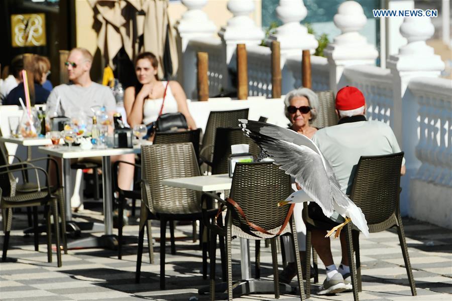 People enjoy sunshine by the seaside in the city of Benidorm, the Province of Alicante, Spain, Feb. 16, 2019. (Xinhua/Guo Qiuda)
