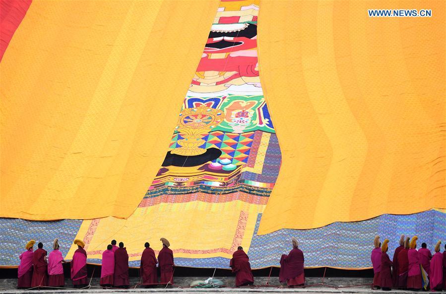 Lamas of the Labrang Monastery uncover the large yellow curtain on a huge thangka scroll painting bearing the image of the Buddha during the annual \