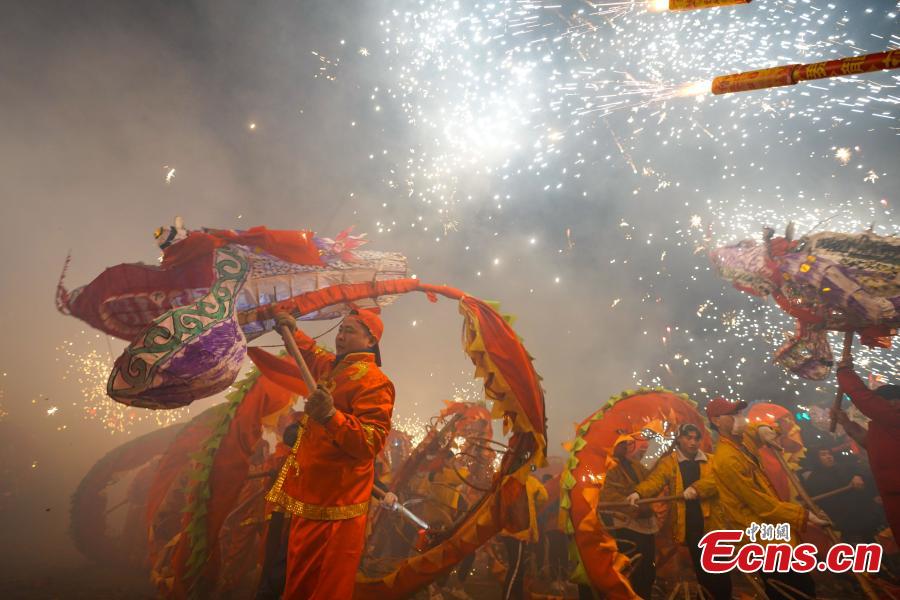 People perform dragon dance with a background of firecrackers in Yuqing County, southwest China\'s Guizhou Province, Feb. 16, 2019. Villagers gathered and performed dragon dances to celebrate the upcoming Lantern Festival,which falls on Feb. 19 this year. (Photo/China News Service)