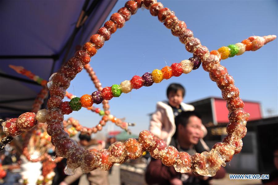 Tourists walk past booths selling tanghulu, a traditional Chinese snack of candied fruit, during an activity to greet the upcoming Lantern Festival in Lihua Village of Renqiu, north China\'s Hebei Province, Feb. 17, 2019. The traditional Chinese Lantern Festival falls on Feb. 19 this year. (Xinhua/Mu Yu)
