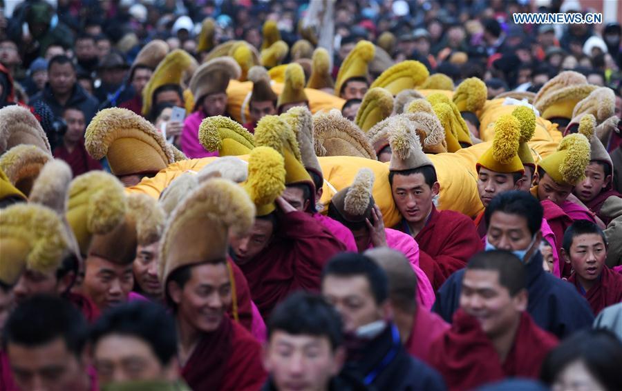 Lamas of the Labrang Monastery shoulder a huge thangka scroll painting bearing the image of the Buddha towards a nearby Buddha-exhibition hill during the annual \
