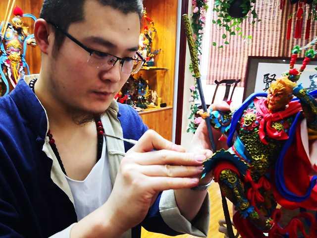 Gong Yuze focuses his attention on a dough figurine as he works in his studio in Harbin, capital of Northeast China\'s Heilongjiang Province. (Photo by Zhang Qingyun for chinadaily.com.cn)