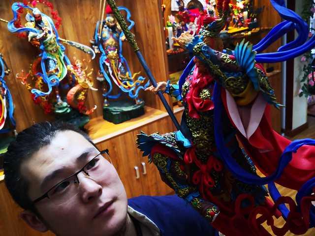 Gong Yuze presents a dough figurine in his studio in Harbin, capital of Northeast China\'s Heilongjiang Province. (Photo by Zhang Qingyun for chinadaily.com.cn)