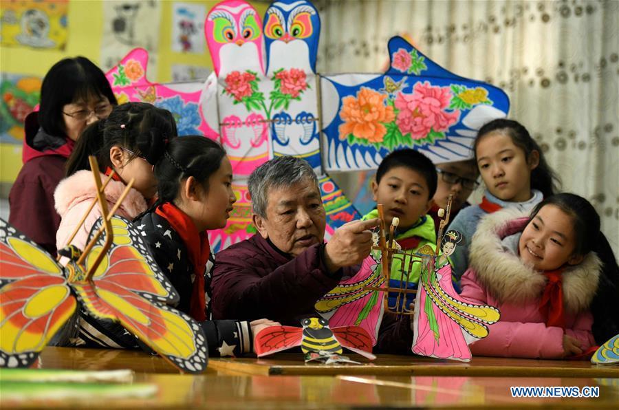 Kite enthusiast Fu Xianming gives a lesson on kite-making during a workshop at Xili Primary School in Shijiazhuang, north China\'s Hebei Province, Feb. 20, 2019. Fu Xianming and his wife Lin Wenqing are known for their passion for kites. The retired school-teacher couple has completed more than 1,500 kites since they began to learn kite-making in 1998. Driven by a wish to master the kite-making crafts, Fu and Lin went on multiple study tours to Weifang, Shandong Province, where traditional Chinese kites originated. Besides enjoying themselves, the couple has also set up a campus workshop for local students who show interest in kite-making. (Xinhua/Chen Qibao)