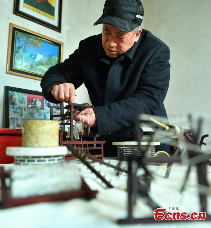 Wang Xiangcheng shows his handmade miniature agricultural tools in his home in a village in Baoding City, North China\'s Hebei Province, Feb. 25, 2019. Wang has built more than a dozen sets of models of old farming objects, such as ploughs, carriages, looms and stone mills, at a scale of 1:8. He said he hoped his models could provide younger generations with a glimpse of what life was like in the countryside in years past. (Photo: China News Service/Zhai Yujia)