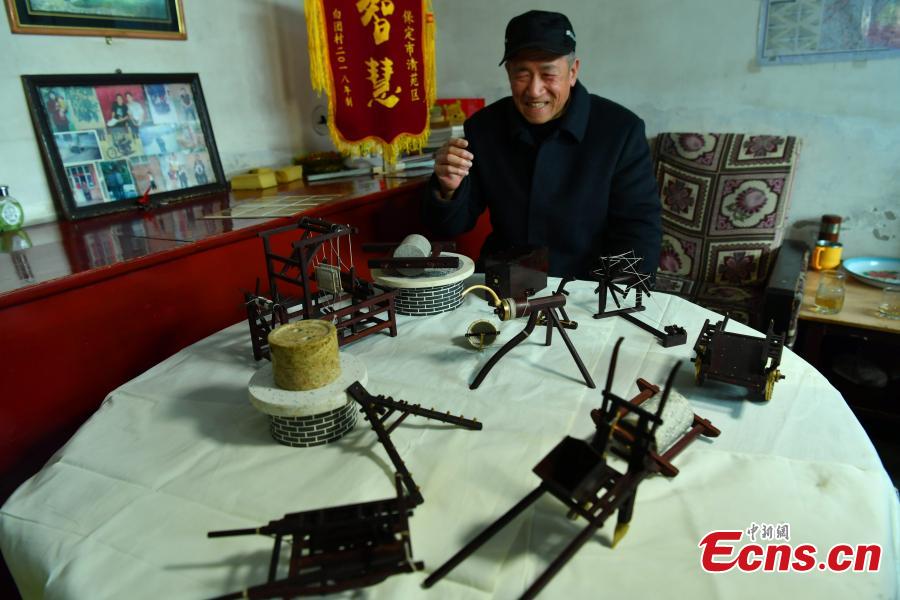 Wang Xiangcheng shows his handmade miniature agricultural tools in his home in a village in Baoding City, North China\'s Hebei Province, Feb. 25, 2019. Wang has built more than a dozen sets of models of old farming objects, such as ploughs, carriages, looms and stone mills, at a scale of 1:8. He said he hoped his models could provide younger generations with a glimpse of what life was like in the countryside in years past. (Photo: China News Service/Zhai Yujia)