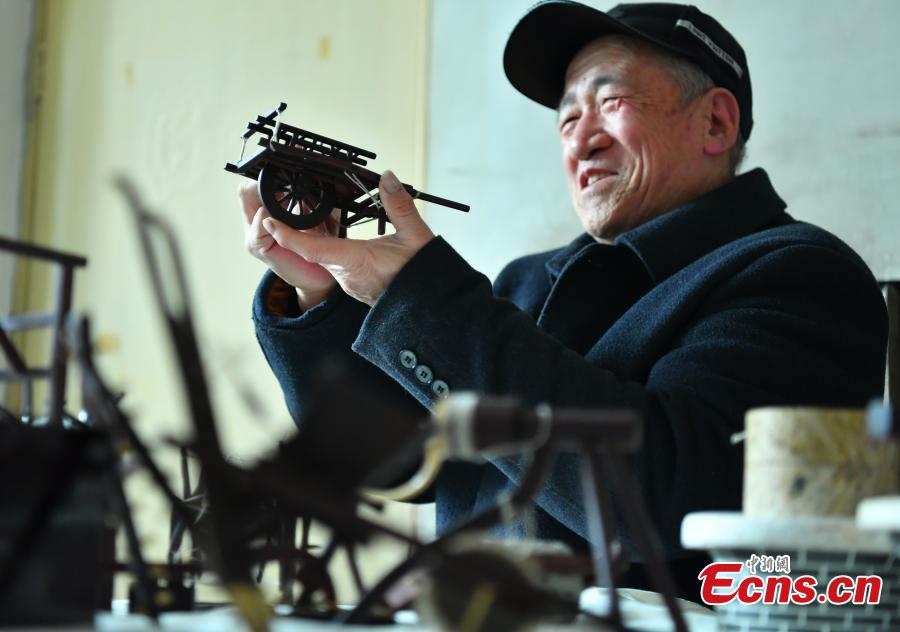 Wang Xiangcheng shows his handmade miniature agricultural tools in his home in a village in Baoding City, North China\'s Hebei Province, Feb. 25, 2019. Wang has built more than a dozen sets of models of old farming objects, such as ploughs, carriages, looms and stone mills, at a scale of 1:8. He said he hoped his models could provide younger generations with a glimpse of what life was like in the countryside in years past. (Photo: China News Service/Zhai Yujia)