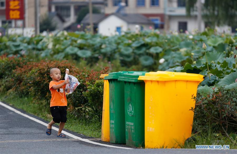 A child prepares to put trash into a classified garbage bin at Gangkou Village of Anji County, east China\'s Zhejiang Province, Aug. 16, 2018. As \