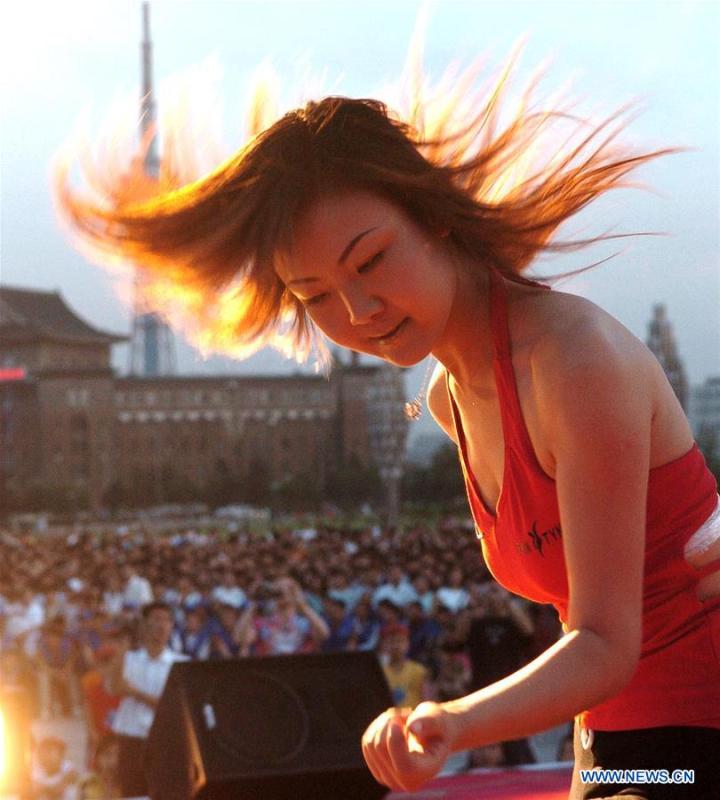 A girl flings her hair during a hip hop competition at a square in Changchun, capital of northeast China\'s Jilin Province, June 6, 2004. Along with China\'s reform and opening-up starting from 1978, Chinese women have refreshed their images year after year, which can be simply seen from their hairstyles. Women\'s hairstyles, just like a mirror, reflect fashion changes and most importantly, Chinese women\'s increasingly diversified definition of beauty. (Xinhua/Xu Jiajun)