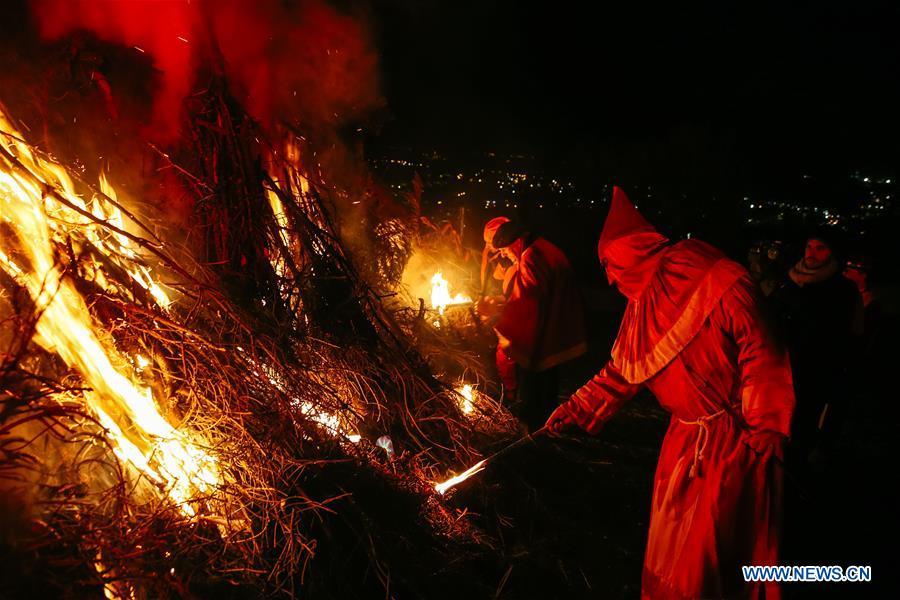 Local residents wearing traditional costumes light the bonfire during the \