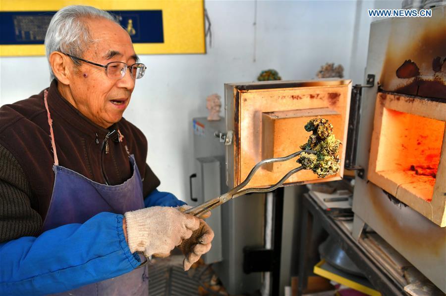 Ge Yuansheng, inheritor of coloured glaze firing skill, a national intangible cultural heritage listed in 2008, works on a piece of coloured glaze made of coal cinder at his workshop in Taiyuan, north China\'s Shanxi Province, March 13, 2019. Ge has been applying his skill of coloured glaze firing to waste coal cinder for five years. After going through dozens of processes, the waste material would be made into delicate artwork. (Xinhua/Cao Yang)