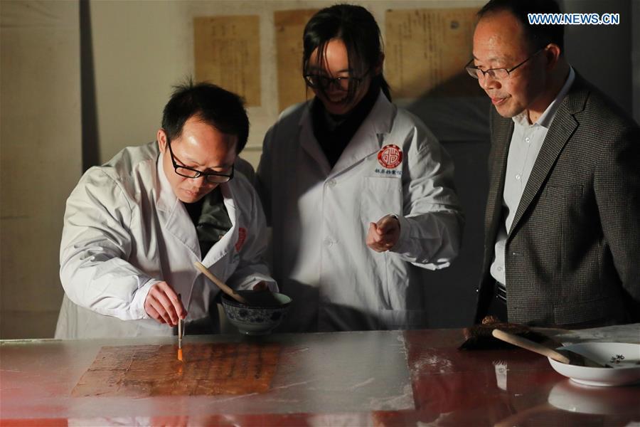Wang Zongxun (R), curator of a museum of Jinping Writs, looks on as staff workers conduct paper-pasting on a document at the museum in Jinping County, southwest China\'s Guizhou Province, March 18, 2019. Dating back to the Ming Dynasty (1368-1644), \