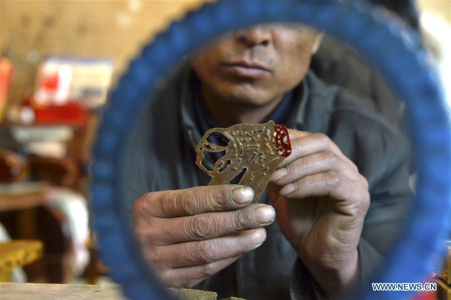 Zhou Zhibing, the apprentice of Pan Mingsheng, applies dye to the shadow puppet at Xinzhai Township of Weiyuan County in Dingxi City, northwest China\'s Gansu province, March 13, 2019. Many local folk artists concentrate on inheriting and passing down the folk art of shadow puppet performing and making in Gansu. They devote themselves to the study of the art and also organize various events to popularize the art. (Xinhua/Li Xiao)