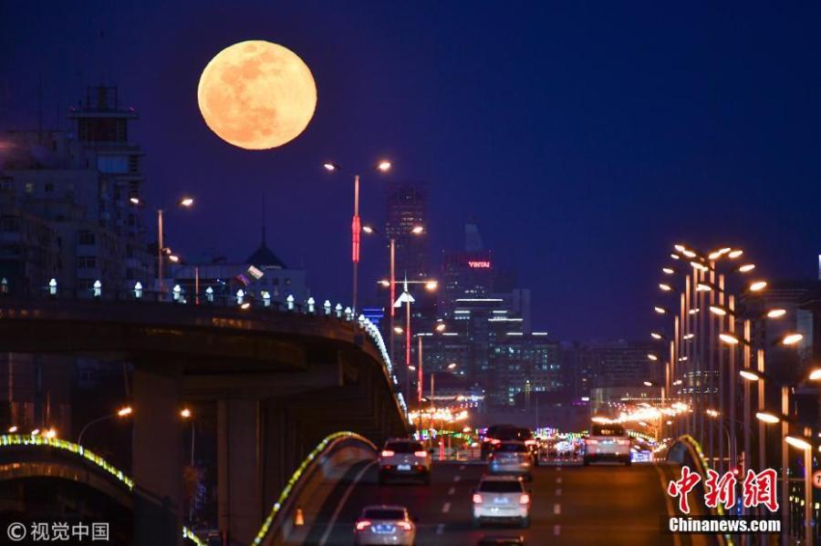 A super snow moon rises over Chang\'an Avenue, a major thoroughfare in Beijing, March 21, 2019. Sky-watchers received a treat as the final supermoon of 2019 arrived on Thursday, also the Spring Equinox, which signals the equal length of day and night time. A supermoon occurs when a full moon\'s orbit is closest to the Earth.  (Photo/VCG)