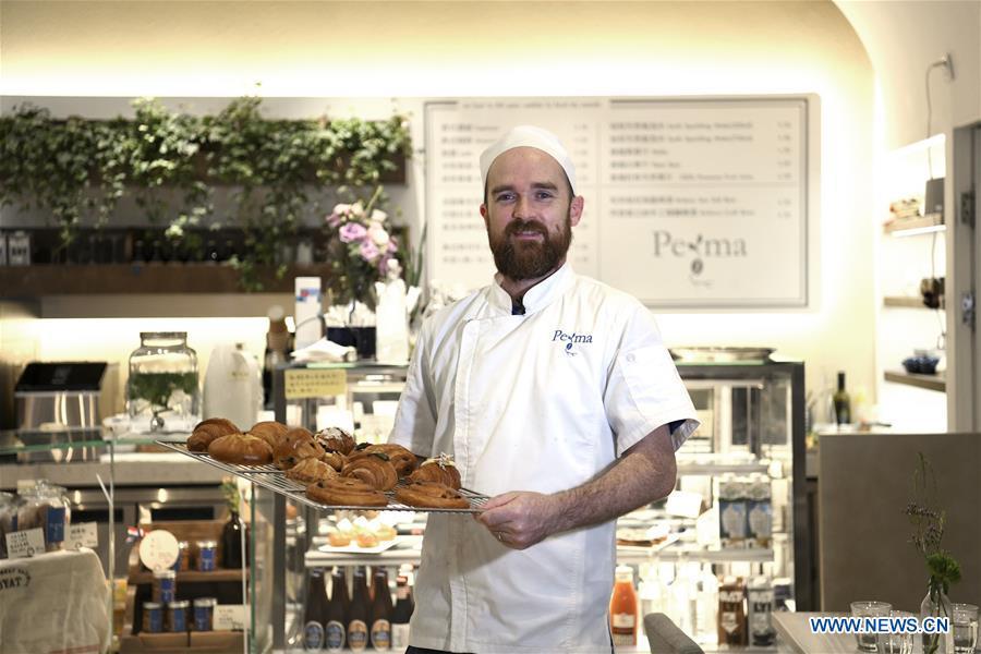 French baker Christophe poses for a photo with bread he made at his bakery store in Guangzhou, south China\'s Guangdong Province, March 21, 2019. French baker Christophe and his wife Agnes started their first French bakery store called \