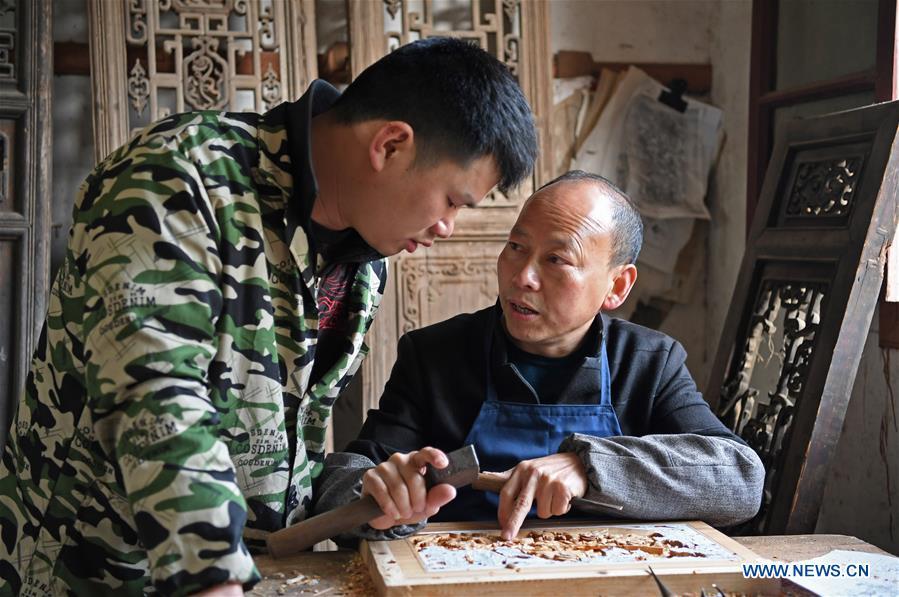 Yu Youhong teaches his apprentice the techniques on carvings in Wuyuan County of east China\'s Jiangxi Province, March 19, 2019. The \