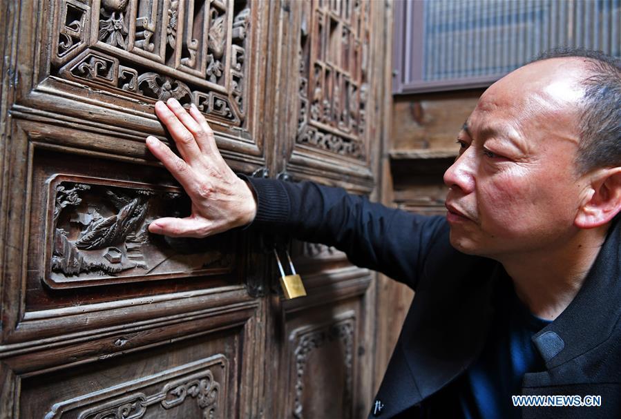 Yu Youhong checks a broken carving work on wood inside an ancient building in Zhangcun Village, Wuyuan County of east China\'s Jiangxi Province, March 19, 2019. The \