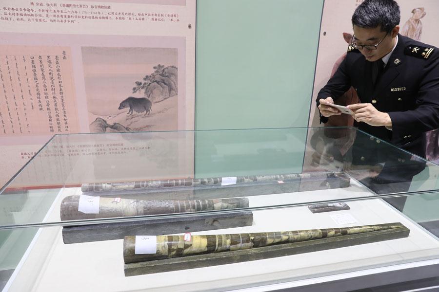 A customs officer takes a photo of an orthoceras fossil at the Beijing Museum of Natural History on March 27, 2019. (Photo/Asianewsphoto)