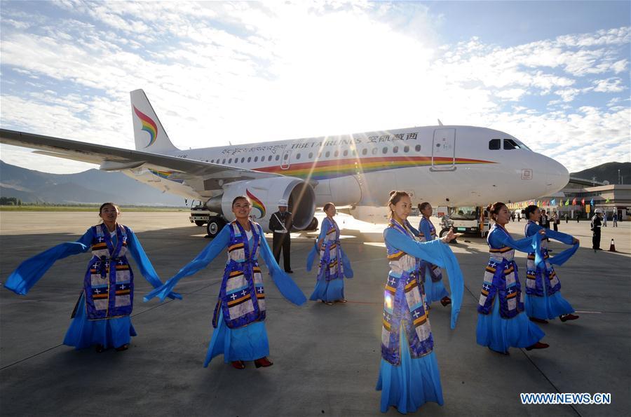 Performers give a dance performance beside a plane of the Tibet Airlines which prepares to take off at the Lhasa Gonggar Airport, southwest China\'s Tibet Autonomous Region, July 26, 2011. Infrastructure has been improved in Tibet, as a comprehensive transportation network composed of highways, railways and air routes has been formed. (Xinhua/Chogo)