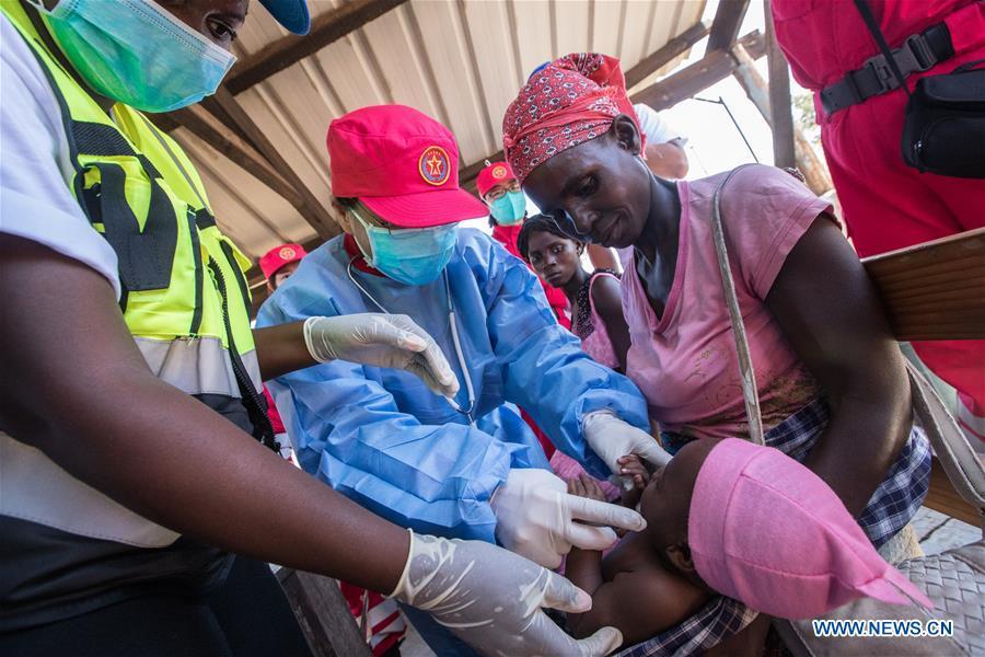 A member of Chinese rescue team examines a child in Lamago Village, 90 km from Beira, Mozambique, March 26, 2019. A Chinese rescue team went to Lamago Village to carry out disaster relief work on Tuesday. (Xinhua/Zhang Yu)
