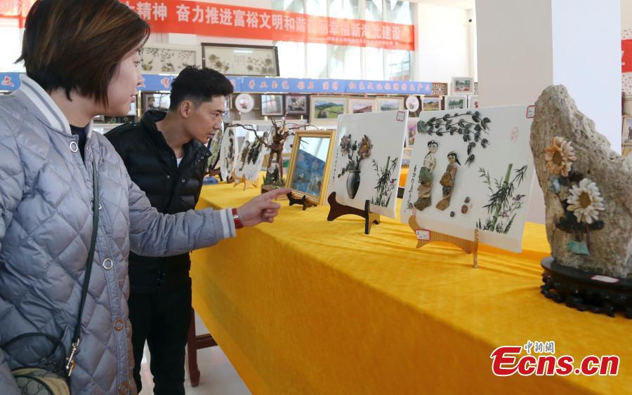 Visitors look at handicrafts made by Wang Zhongxiang using discarded jade fragments in Qilian County, Northwest China\'s Qinghai Province, March 28, 2019. The 55-year-old folk artist is known for his ability to turn the waste into valuable works of art often through time-consuming processes, such as polishing, painting and pasting. (Photo: China News Service/Ma Mingyan)