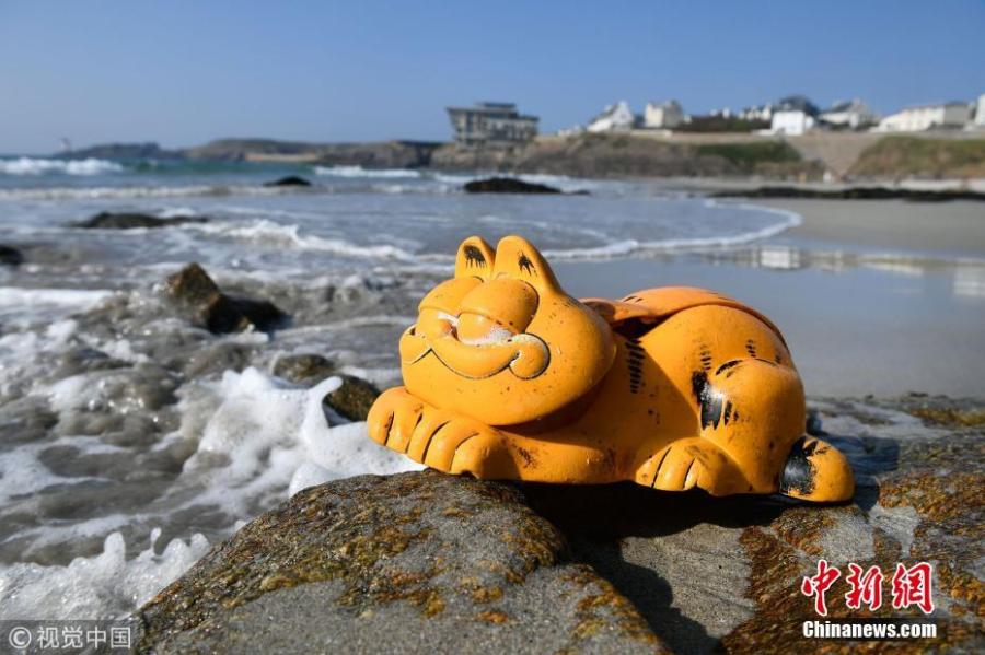 A plastic \'Garfield\' phone is displayed on the beach in Le Conquet, western France. Since the 1980s, the Iroise coast in French coastal community Brittany has received a supply of bright orange landline novelty phones shaped like the famous cartoon cat. Now the source of the problem has been found - a lost shipping container. (Photo/VCG)