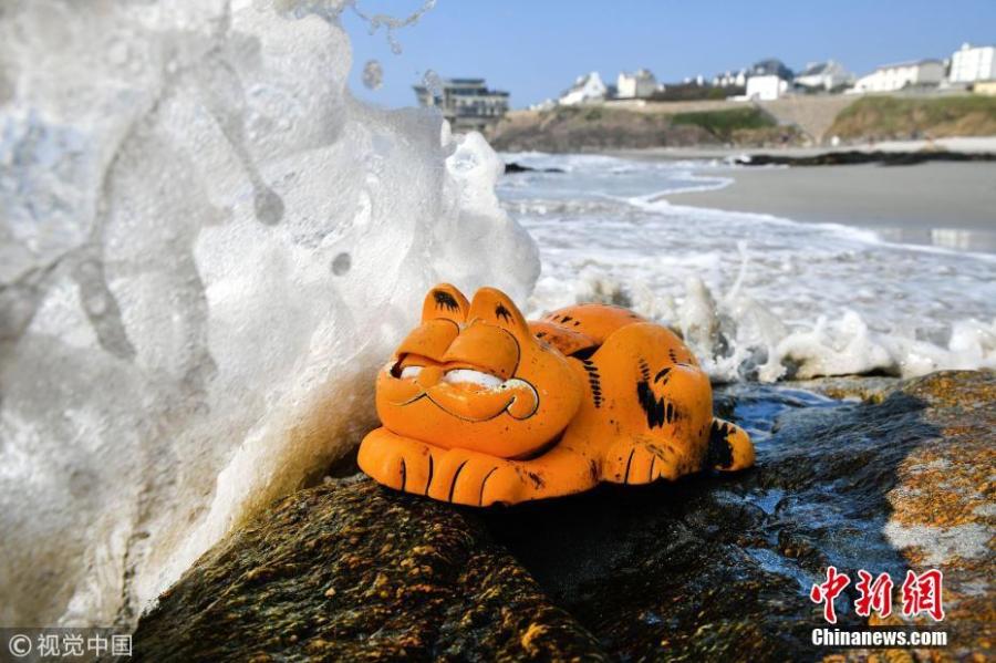 A plastic \'Garfield\' phone is displayed on the beach in Le Conquet, western France. Since the 1980s, the Iroise coast in French coastal community Brittany has received a supply of bright orange landline novelty phones shaped like the famous cartoon cat. Now the source of the problem has been found - a lost shipping container. (Photo/VCG)