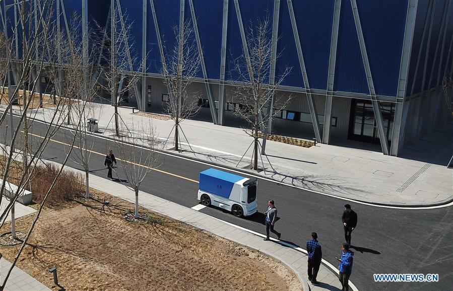 Aerial photo taken on March 31, 2019 shows an unmanned express delivery vehicle running on the street of Xiongan citizen service center in Xiongan New Area, north China\'s Hebei Province. The unmanned express delivery vehicle, independently researched and developed by Cainiao Network, Alibaba\'s logistics arm, was recently put into service at Xiongan citizen service center. The new energy vehicle can convey about 200 small packages at one time from delivery station to intelligent cabinet. (Xinhua/Jin Liangkuai)