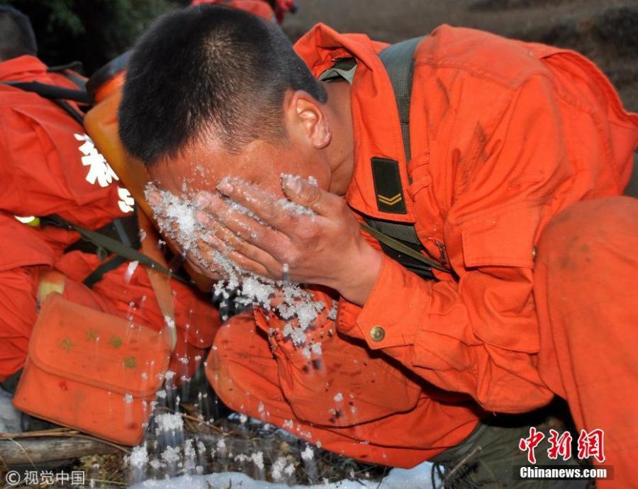 A firefighter puts snow on his face to sooth pain after extinguishing a forest fire, Feb. 6, 2014. (Photo/Agencies)
