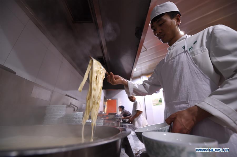 A chef gets noodles from a pot at a beef noodle restaurant in Lanzhou, capital of northwest China\'s Gansu Province, April 2, 2019. Lanzhou beef noodles, a Chinese hand-pulled noodle originated in Lanzhou, has a history of about 100 years. There are about ten types of noodles of different width and shapes, depending on noodle chefs\' pulling skills. It has won fame both at home and abroad with its speciality of noodles and soup recipe. (Xinhua/Fan Peishen)
