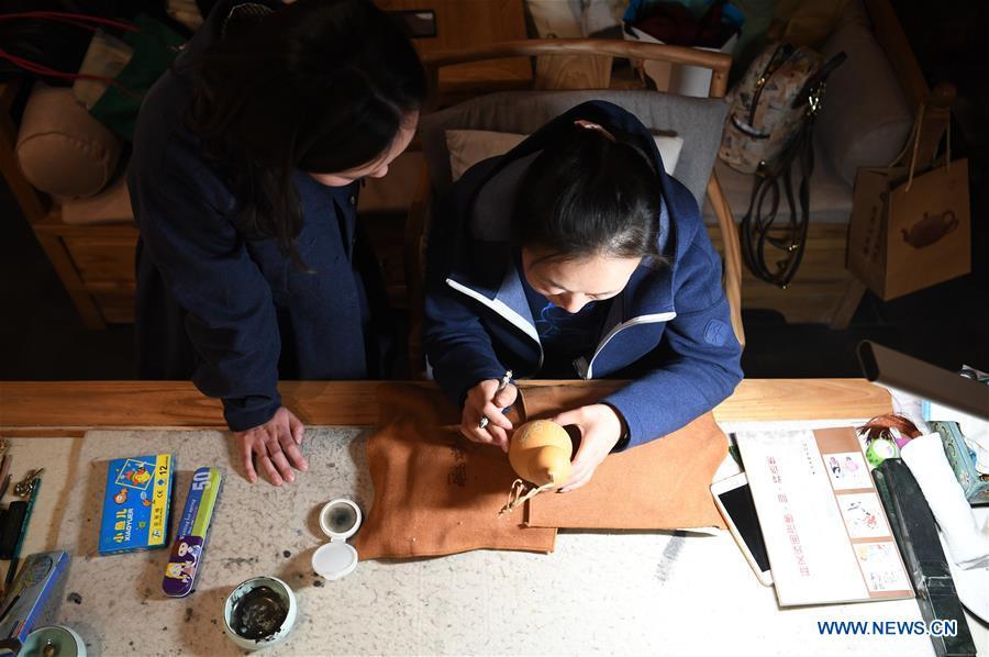 Ruan Xiyue (L), the fourth generation artist of Carved Gourd Ruan, communicates with Ruan Yizhou, an arts and crafts master of Gansu Province, at a gourd carving studio in Lanzhou, northwest China\'s Gansu Province, April 1, 2019. A carved gourd, as the name suggests, is a gourd carved with landscapes, portraits, animals, calligraphy or poems, and then painted with ink. The process of gourd carving includes choosing gourd, painting, engraving and coloring. It was inscribed in the first group of provincial intangible cultural heritages of Gansu in 2006. (Xinhua/Fan Peishen)