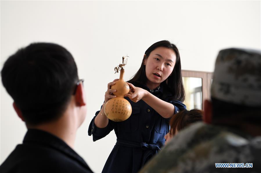Ruan Xiyue, the fourth generation artist of Carved Gourd Ruan, teaches her students at Lanzhou Vocational Technical College in Lanzhou, northwest China\'s Gansu Province, April 1, 2019. A carved gourd, as the name suggests, is a gourd carved with landscapes, portraits, animals, calligraphy or poems, and then painted with ink. The process of gourd carving includes choosing gourd, painting, engraving and coloring. It was inscribed in the first group of provincial intangible cultural heritages of Gansu in 2006. (Xinhua/Fan Peishen)